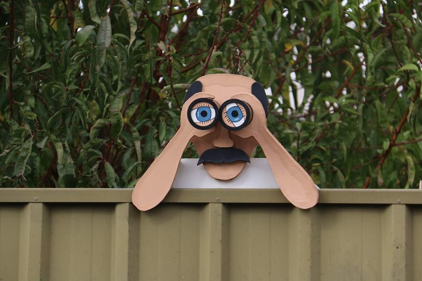 A strange sculpture of a person using binoculars.