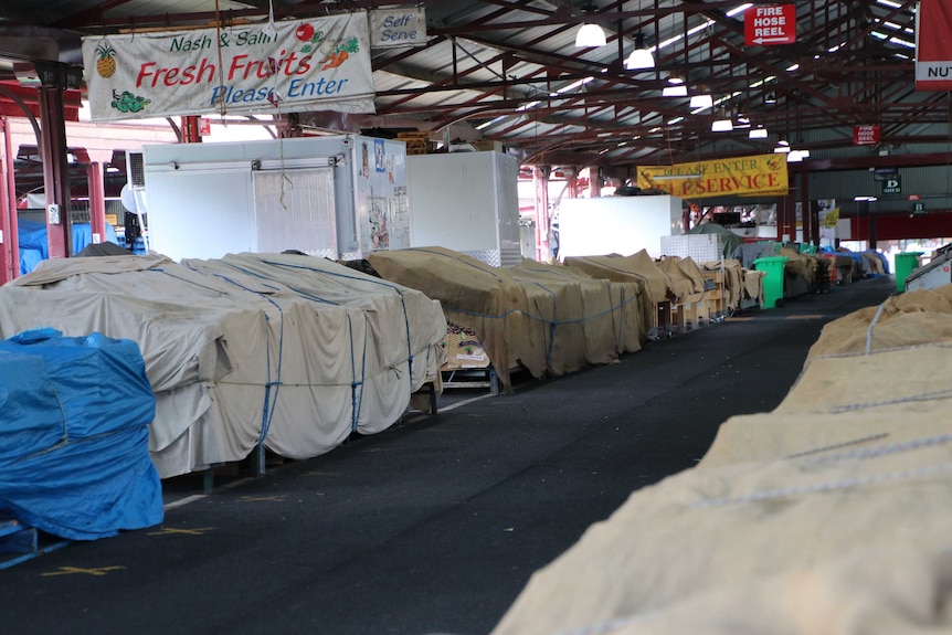 A closed section of Queen Victoria Market where all of the tables are covered in clothes.