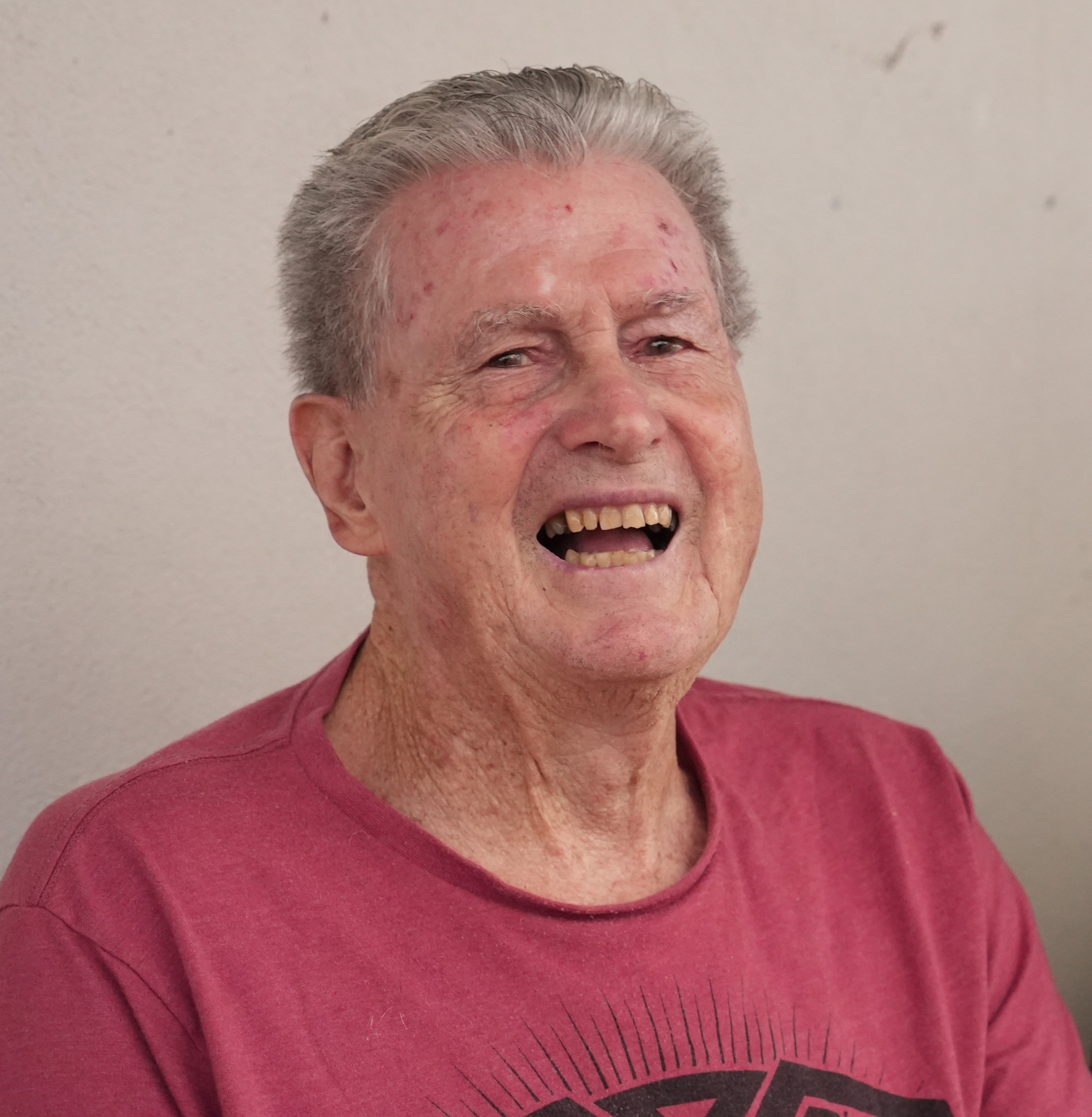 Un anciano con una camiseta roja se ríe.