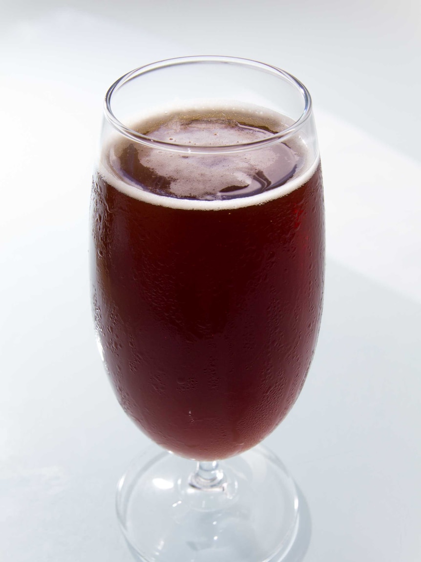 A glass of beer sits on a table.