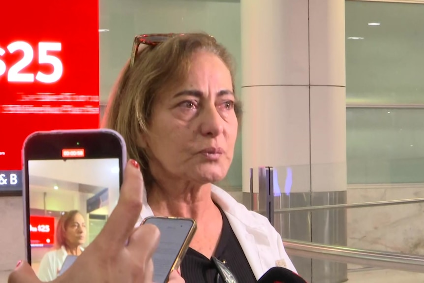 a woman named maryan has tears in her eyes as she speaks to journalists at Sydney airport