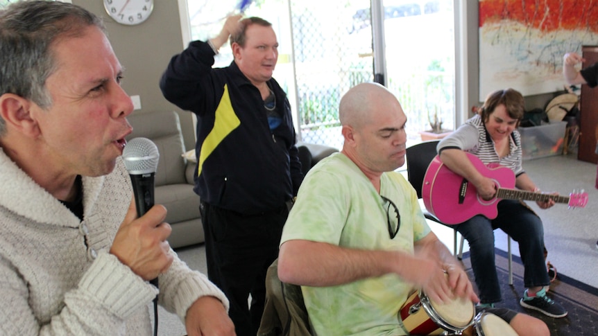 Four adults singing and playing musical instruments