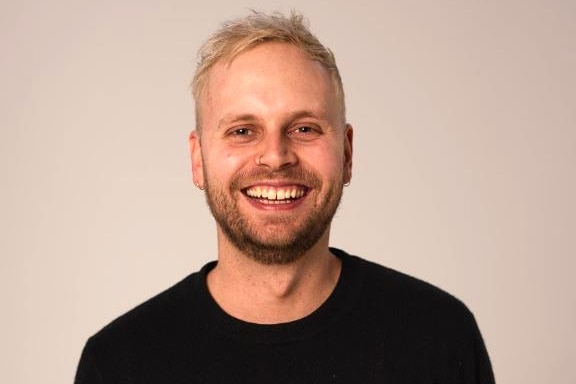 A young man looking at the camera and smiling.