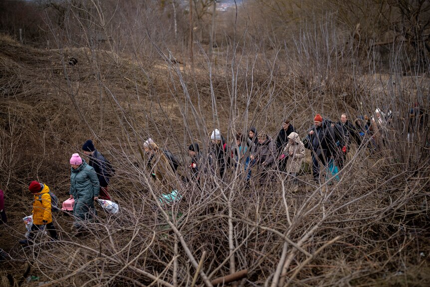 Ukrainian citizens flee crossing the Irpin river in the outskirts of Kyiv.