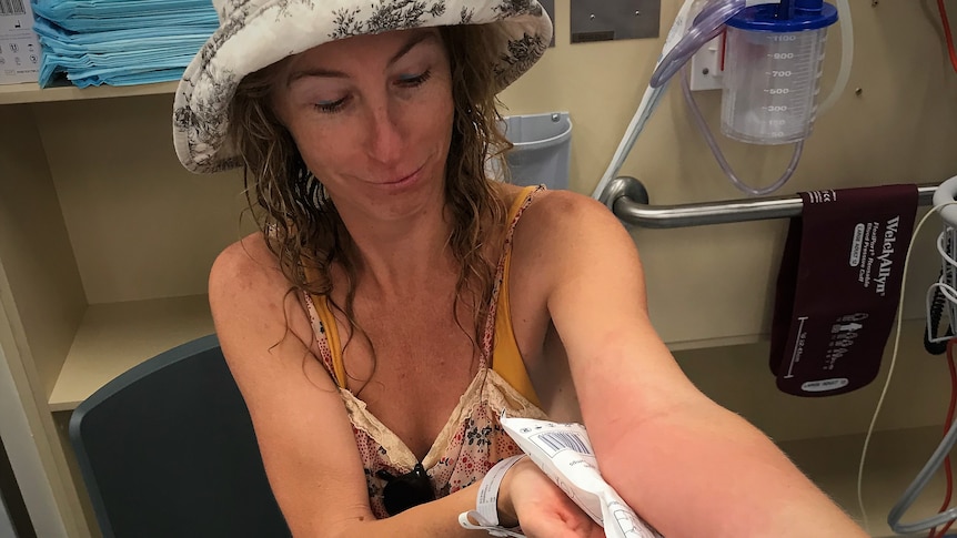 A girl in a sun hat nursing a rash on her left arm.