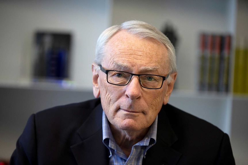 Dick Pound looks into the camera wearing a black suit jacket and blue checked shirt