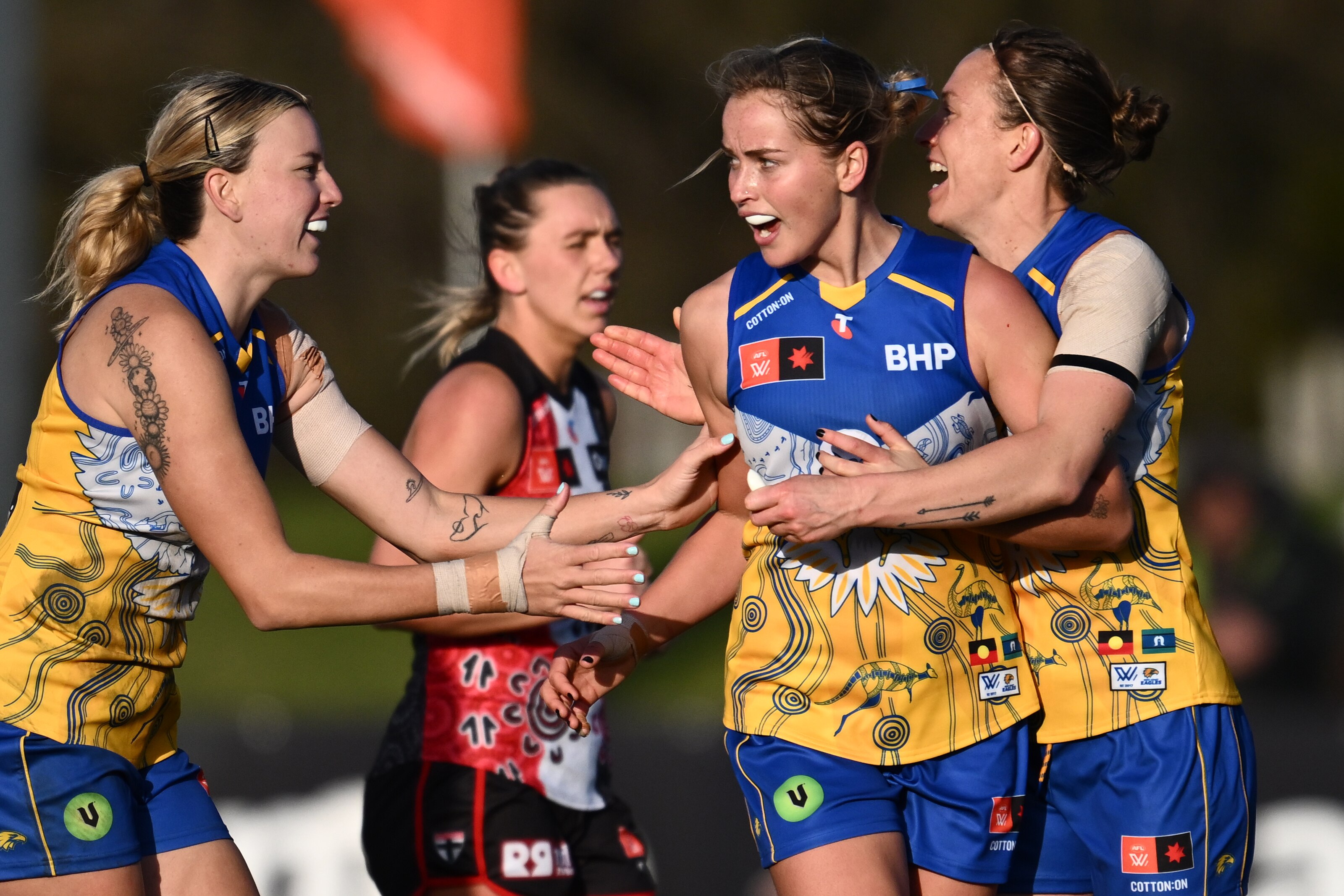 Charlotte Thomas of the Eagles celebrates with two teammates who approach for a hug