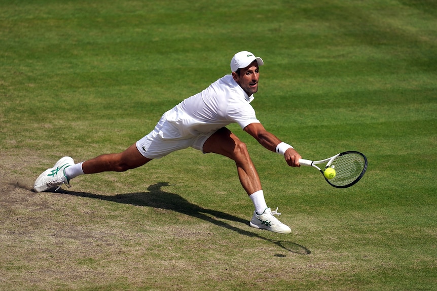 Novak Djokovic slides to his a backhand