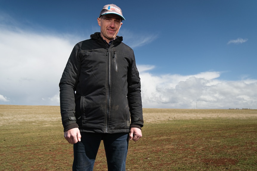 A man stands on a cleared and dry-looking field.