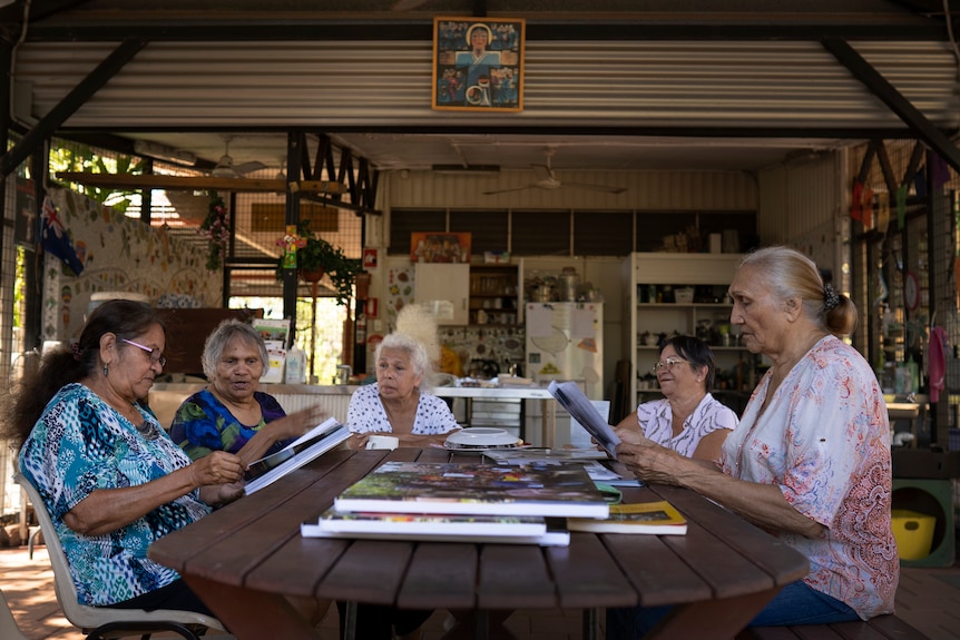 Five women sit around a table.
