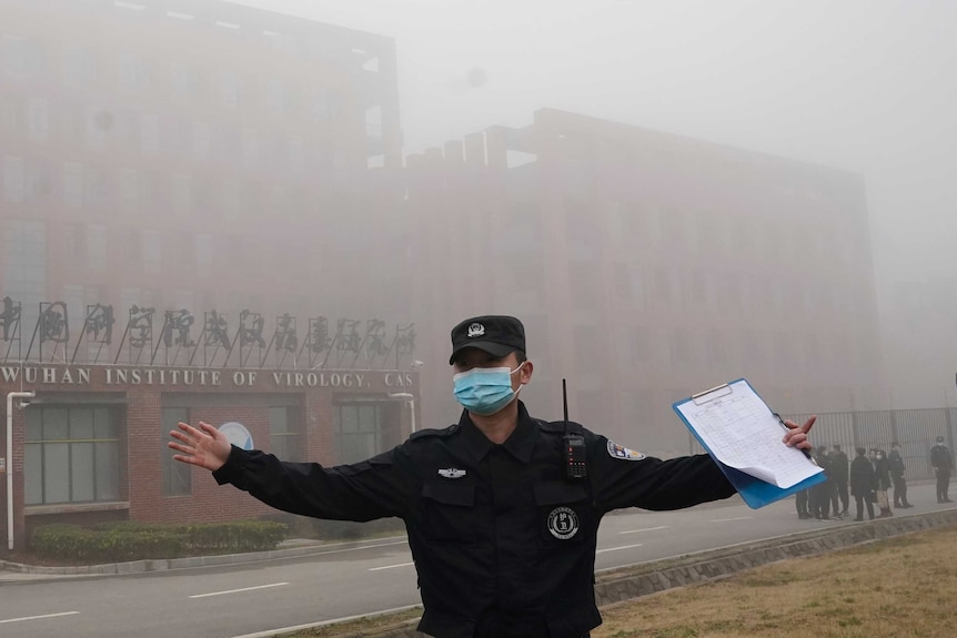 Un uomo della sicurezza tiene i giornalisti lontani dall'Istituto di virologia di Wuhan