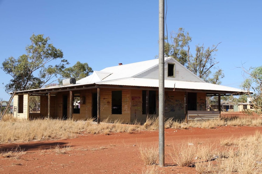 a dilapidated house falling apart in a dry, outback setting