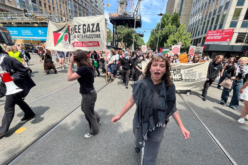 Female teenager wearing a grey top and pants marching in a protest for Palestine in Melbourne.