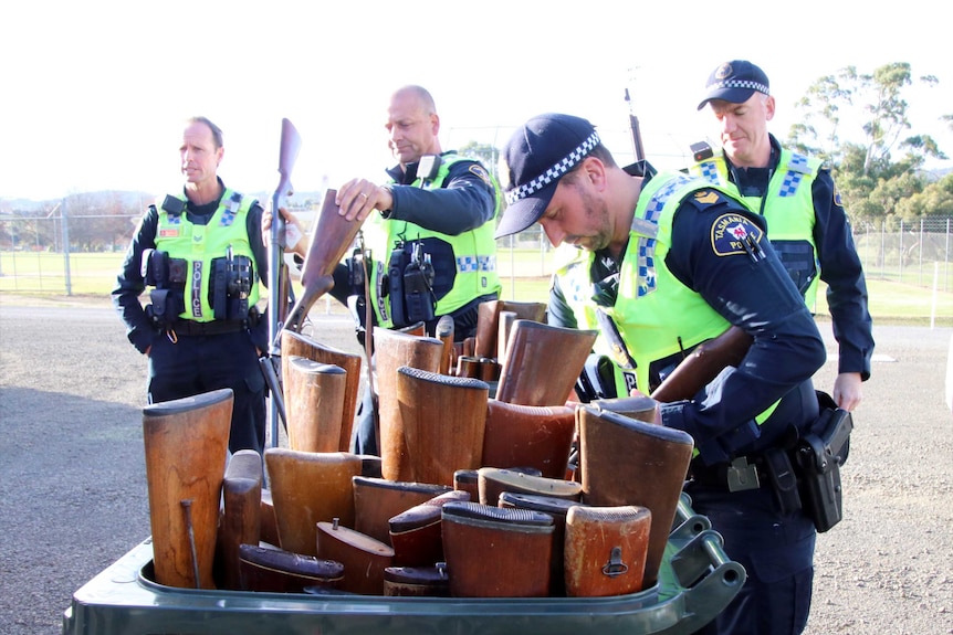 Tasmanian police with a bin of surrendered firearms
