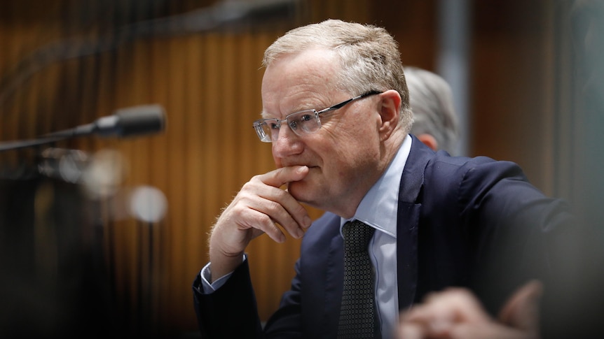 Philip Lowe giving evidence, resting his head on his hand.