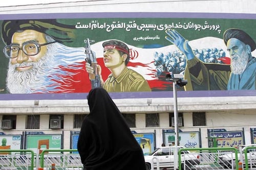 An Iranian woman crosses a street in front of a huge mural painting depicting Iran's supreme leader, Ayatollah Ali Khamenei