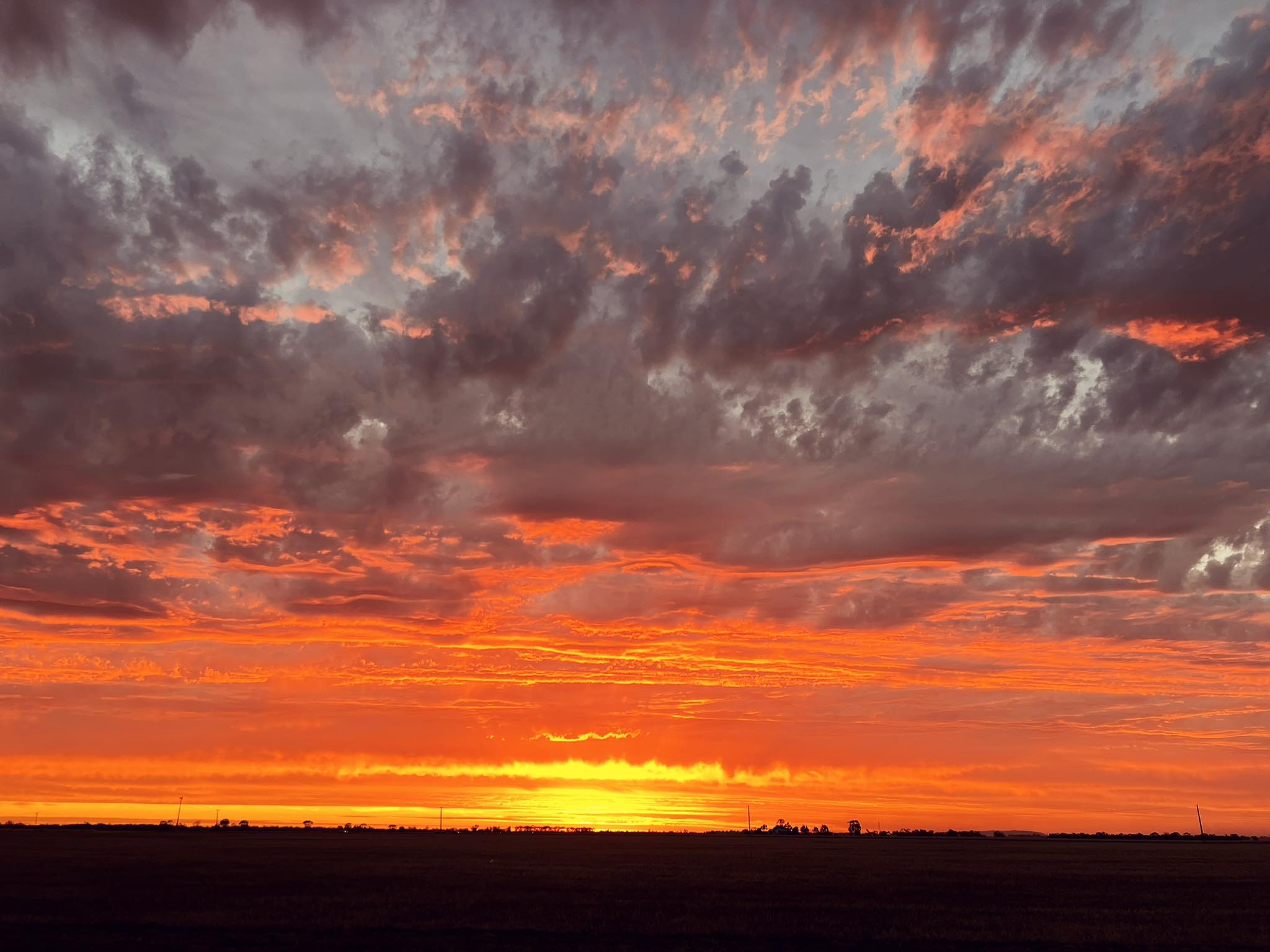 Horizonte oscuro con cielo naranja y nubes grises arriba.