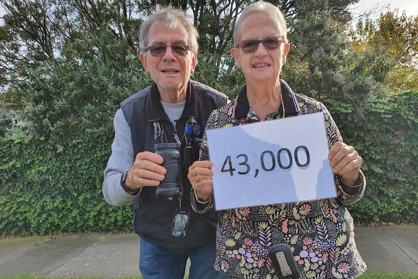 Älteres Ehepaar mit Schild mit der Nummer 43.000.