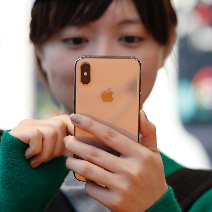 A woman looking at an iPhone XS