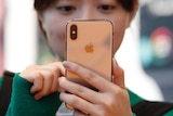 A woman looking at an iPhone XS