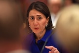 Gladys Berejiklian points her fingers while talking into a microphone.