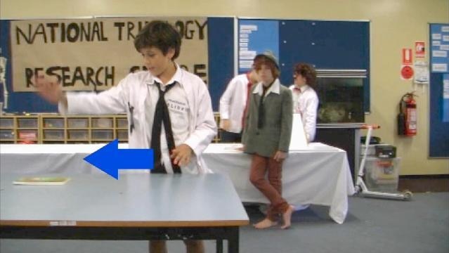 Teenage boy stands at table, graphic arrow points to left of screen