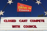 A sign with red letters reading 'closed can't compete with council' under a logo for Tors Drive-In Cinema.