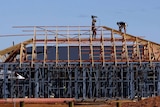 Tradesmen work on the roof of a new house construction