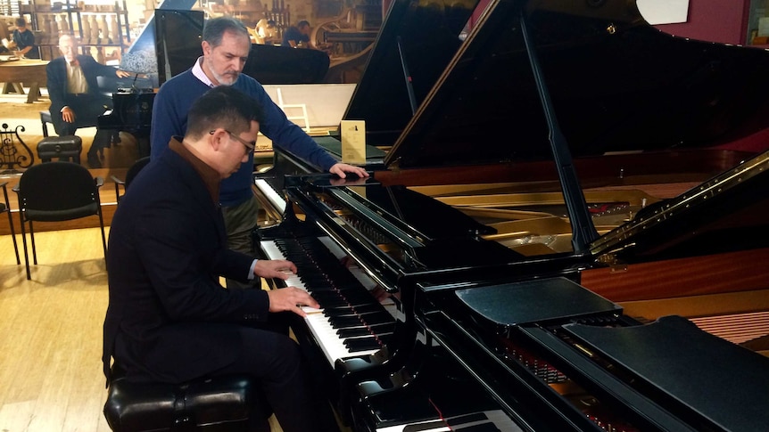 Jason Li tries out the concert piano from the Sydney Opera House Concert Hall while piano technician Are Vartoukian looks on.