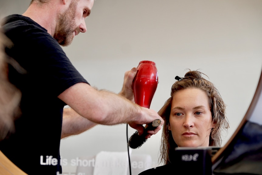 A woman has her hair blow dried in  a salon.