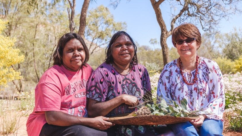 Three women sit down in the desert