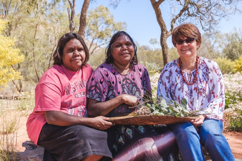 Three women sit down in the desert