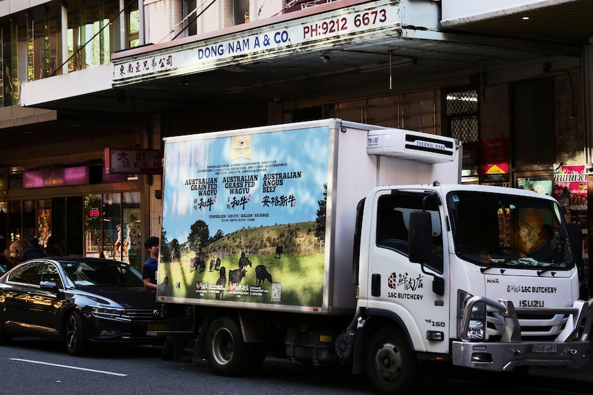 A delivery truck parked in a street in front of grocery stores