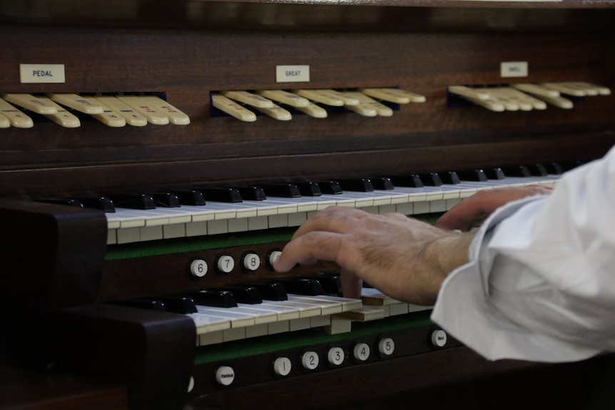 Organ keyboard with hands resting on the keys