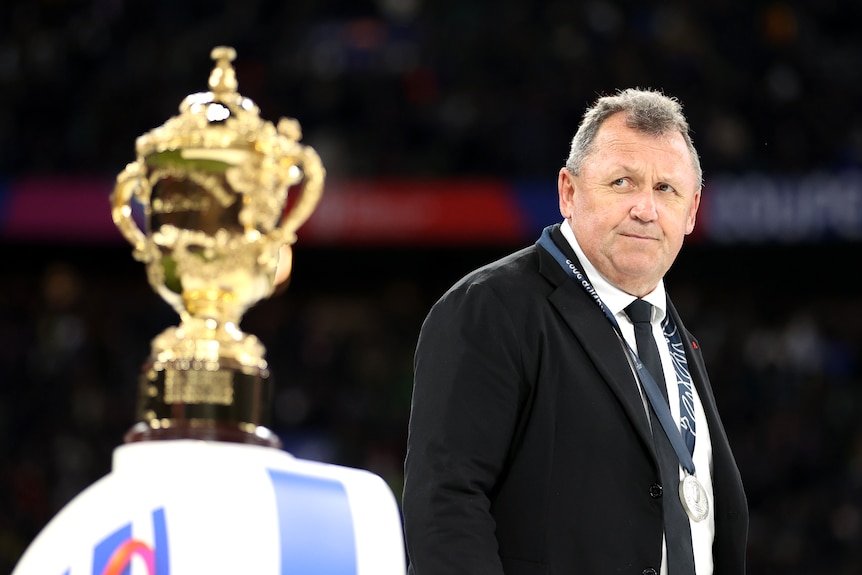 Ian Foster walks on stage with the Webb Ellis Cup in the foreground after the Rugby World Cup final.