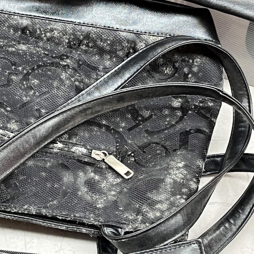 A black handbag covered in mould.