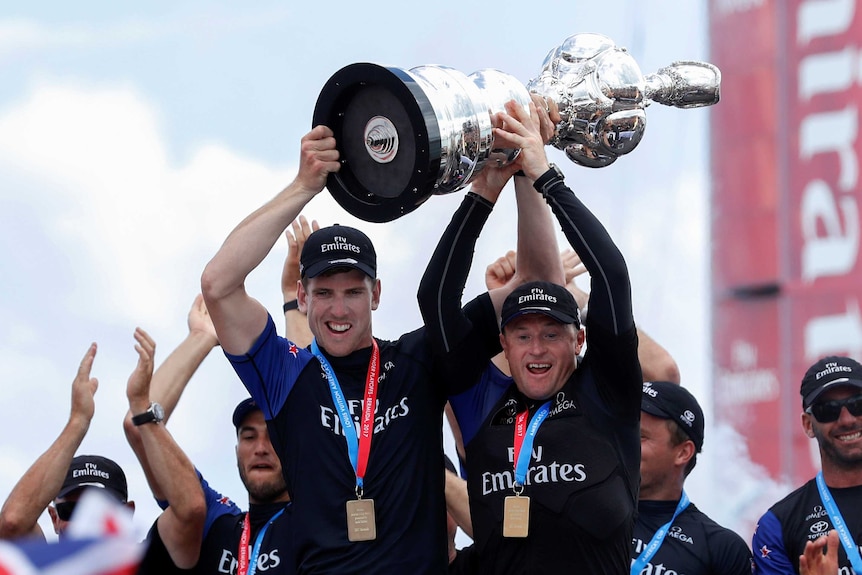 Glenn Ashby (R) and Peter Burling lift the America's Cup trophy after Team New Zealand's victory in Bermuda.