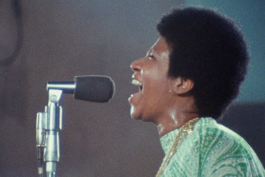 The African American singer Aretha Franklin singing into a microphone in the 1970s