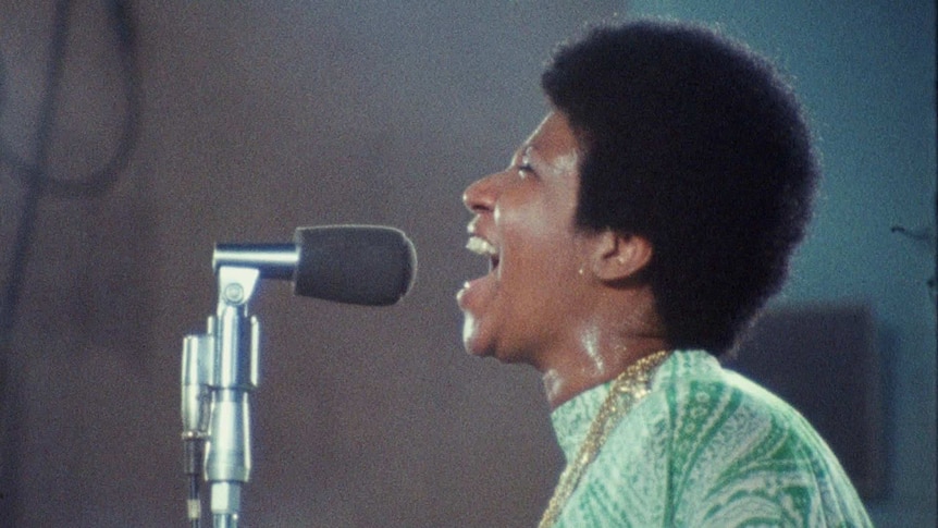 The African American singer Aretha Franklin singing into a microphone in the 1970s