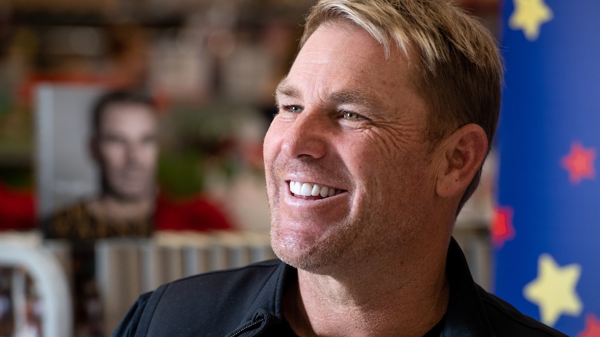 Shane Warne smiles happily.