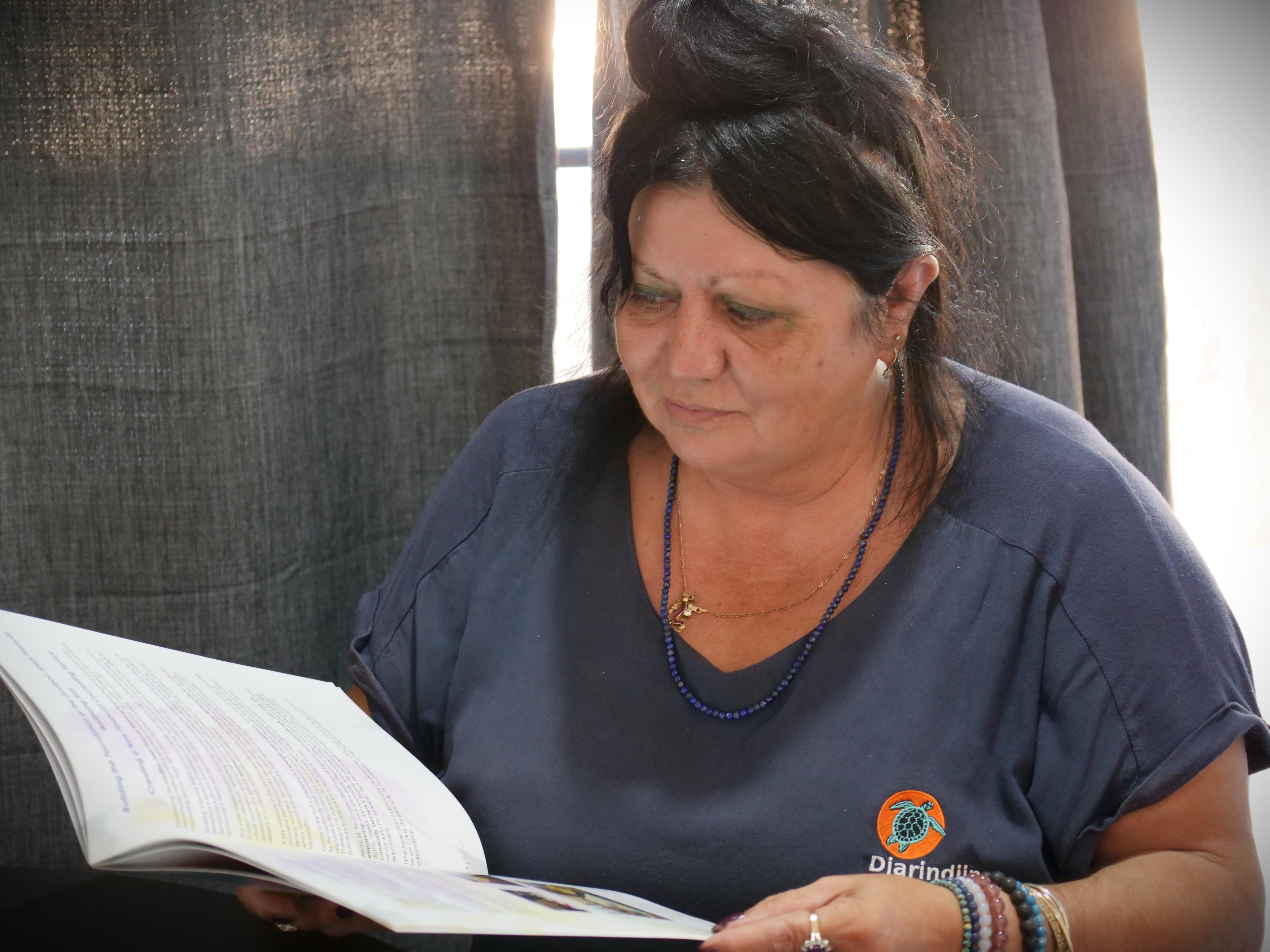Uma mulher de camisa azul olha para o livro.