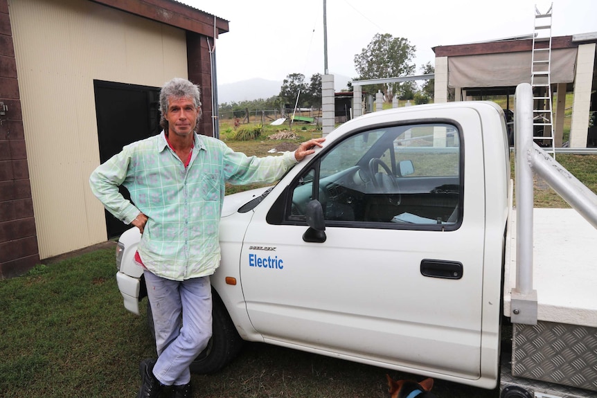 A man leans against a white ute