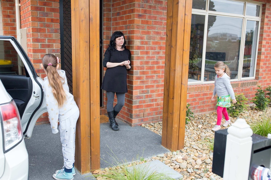 Charlotte Bolcskey waits by the front door as her daughters leave for school.
