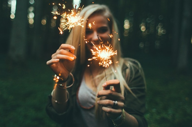 Unidentified woman holding sparklers in a forest.