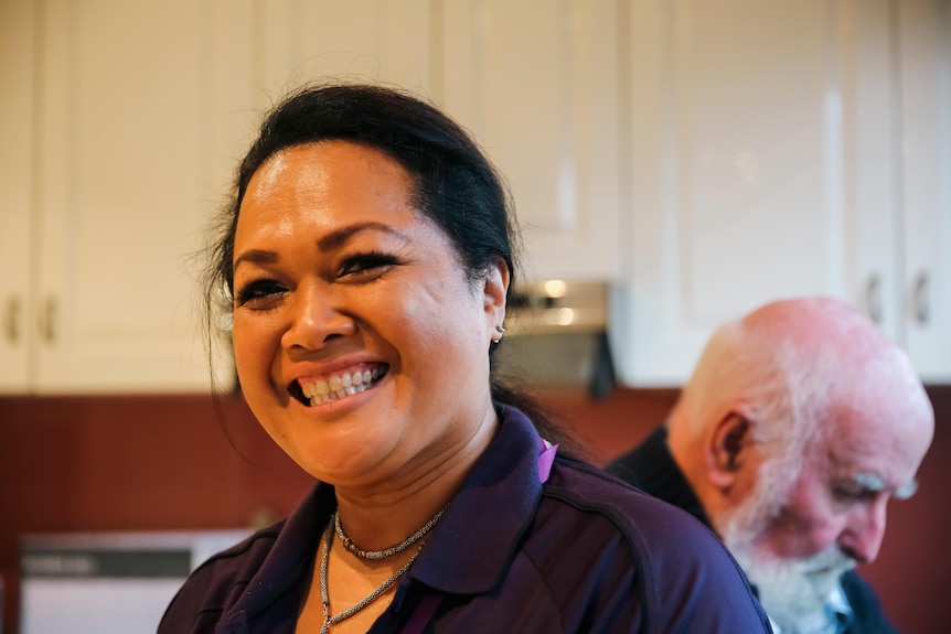 Yanti Hartshorne smiles, standing in a warmly lit kitchen with her client Michael.