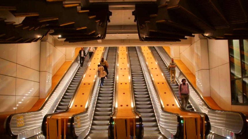 People travelling up and down golden hued escalators
