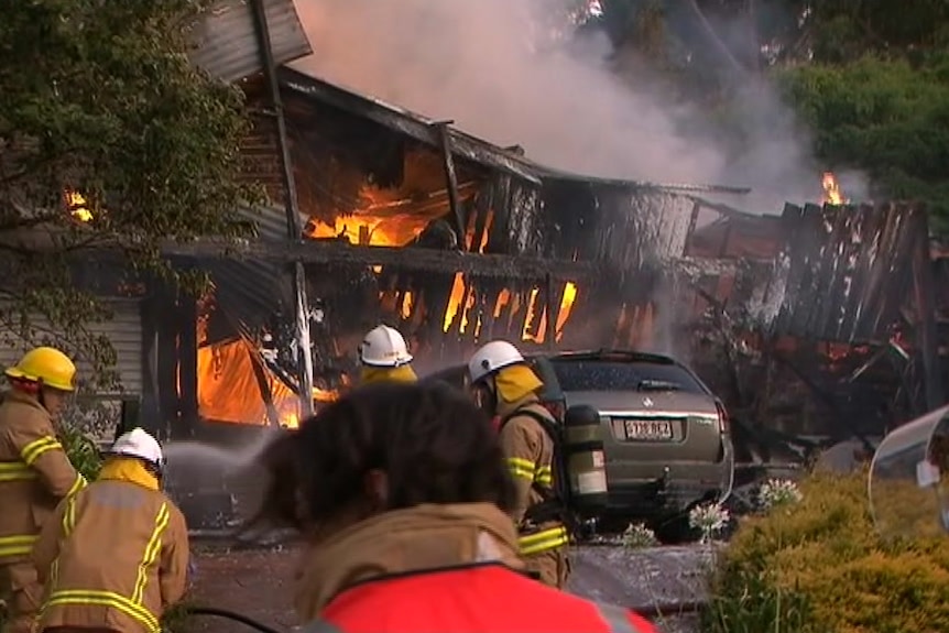 Firefighters at a property engulfed in flames.