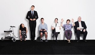 Six people standing and sitting against a white wall
