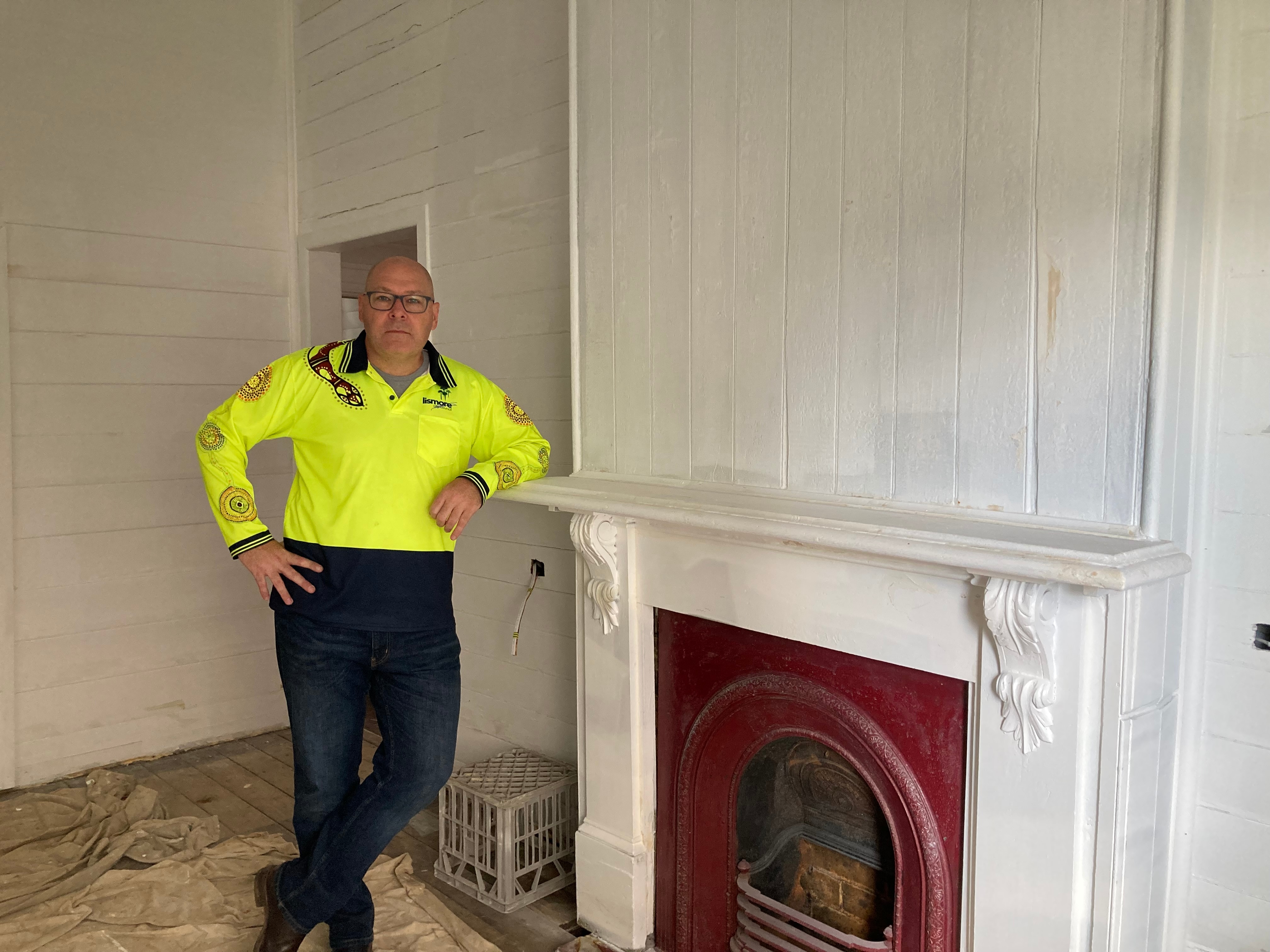 A man poses next to a fire place