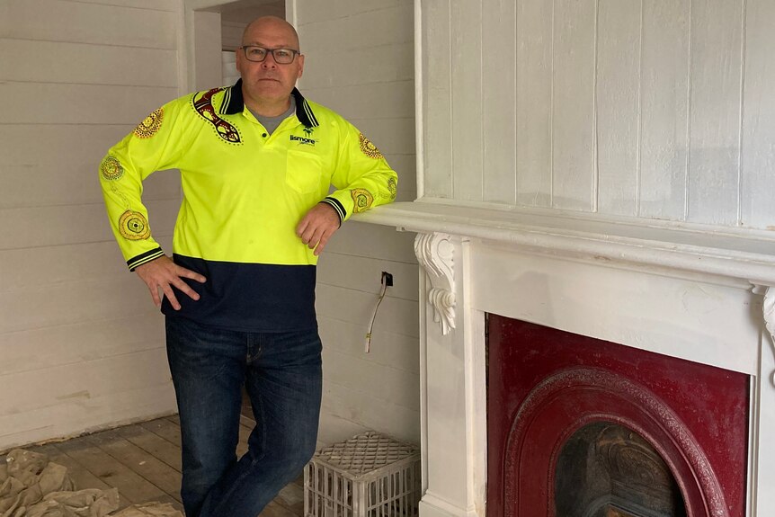 A man poses next to a fire place